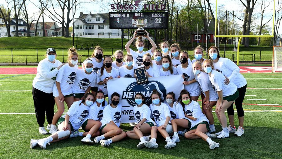 Babson womens lacrosse team lifts NEWMAC trophy.