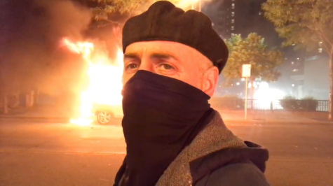 Director Rod Webber, standing in front of a car on fire in Minneapolis during last years Black Lives Matter Protests.