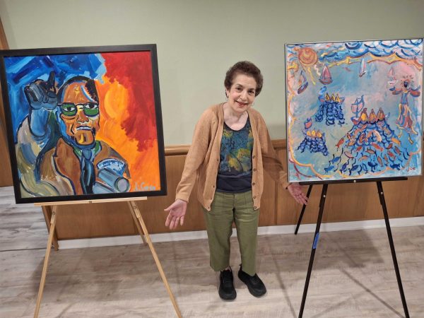 Norine DiCarlo with two of her brother's paintings, "Malcolm X" and "The Great Catch"