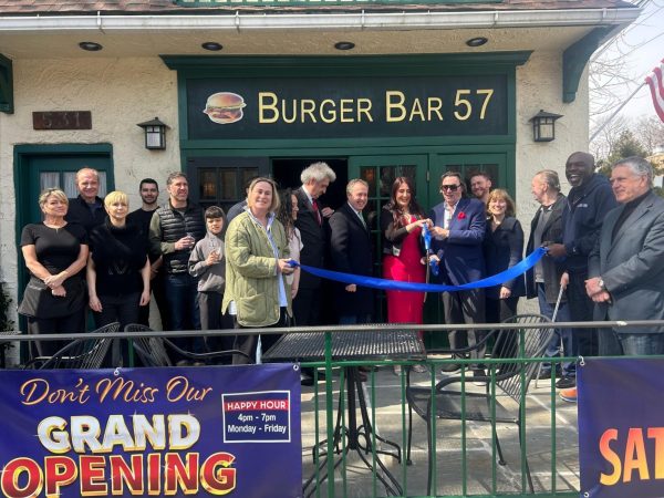 Daniella Lulgjuray of Burger Bar 57, surrounded by town officials and supporters, grabs the scissors for the ribbon-cutting ceremony.